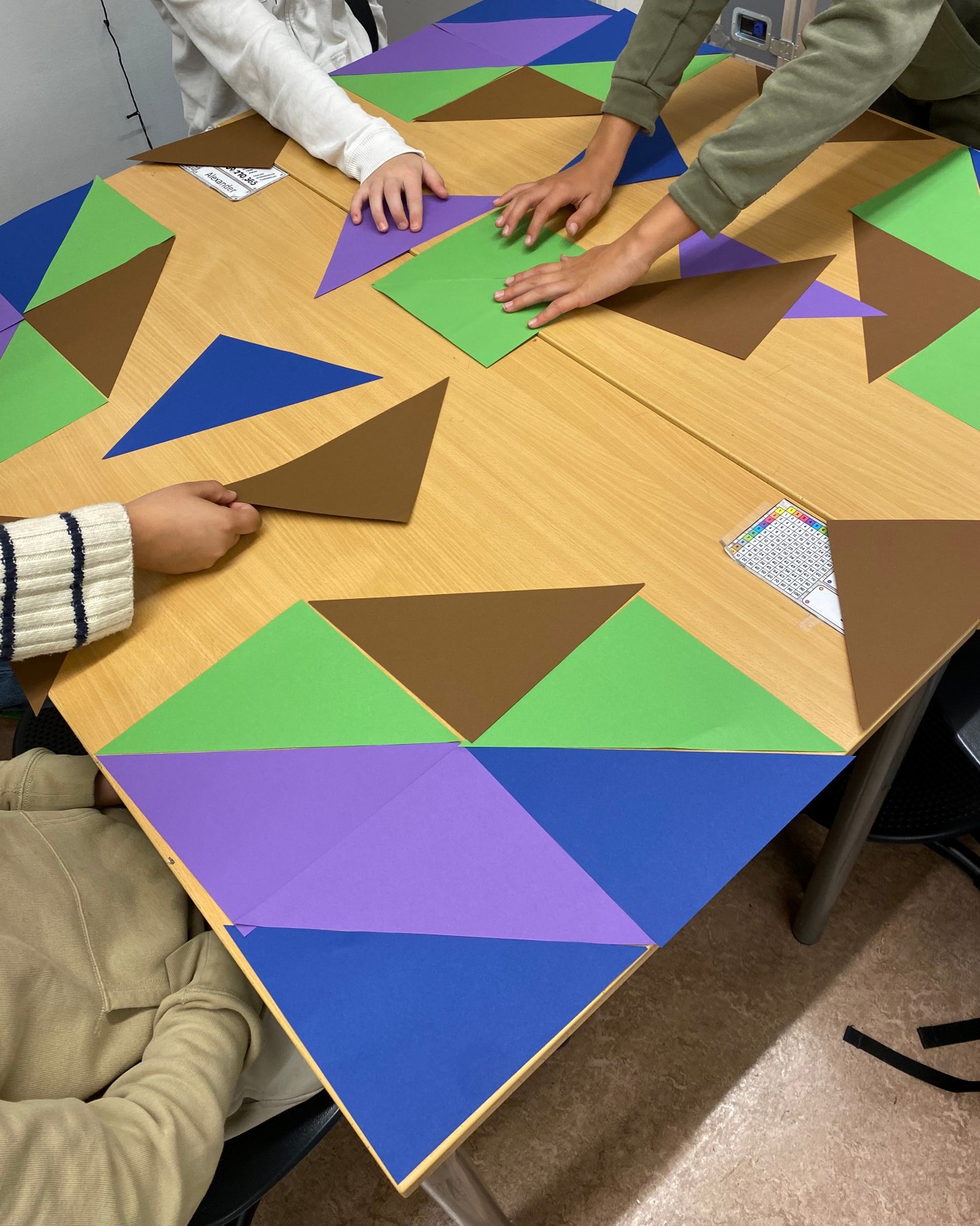 en gruppe mennesker som sitter ved et bord med fargerikt papir på