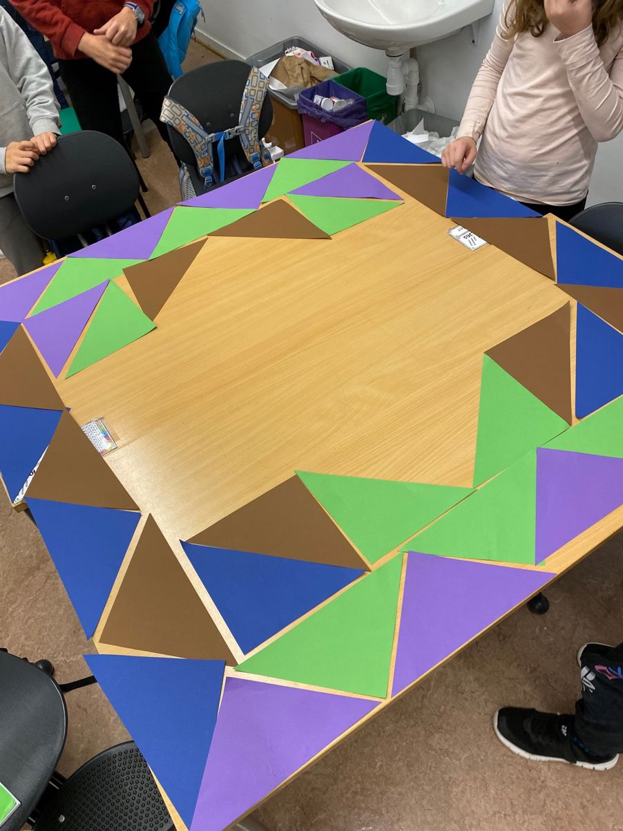 en gruppe mennesker som sitter rundt et bord med fargerike firkanter på